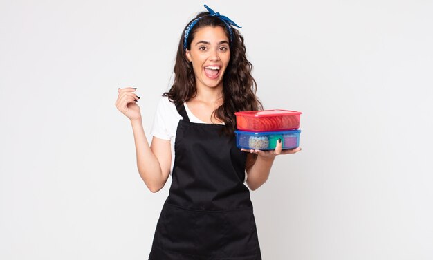 Pretty woman looking happy and pleasantly surprised and holding tupperwares with food