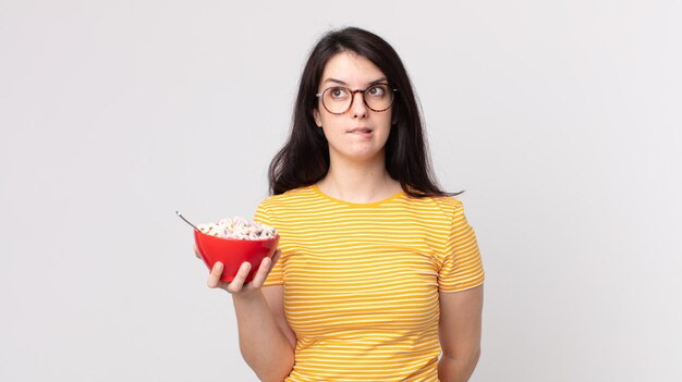 Pretty woman looking puzzled and confused and holding a breakfast bowl