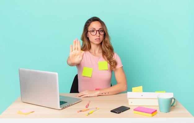 Pretty woman looking serious showing open palm making stop gesture