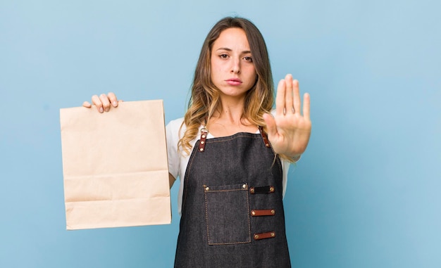 Pretty woman looking serious showing open palm making stop gesture