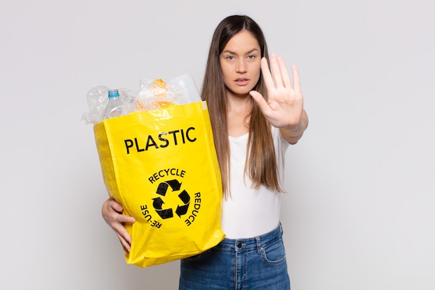 Pretty woman  looking serious, stern, displeased and angry showing open palm making stop gesture