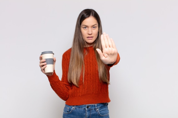 Pretty woman  looking serious, stern, displeased and angry showing open palm making stop gesture