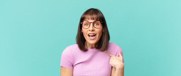 写真 口を大きく開けてショックを受けて驚いたきれいな女性が自分を指さしている