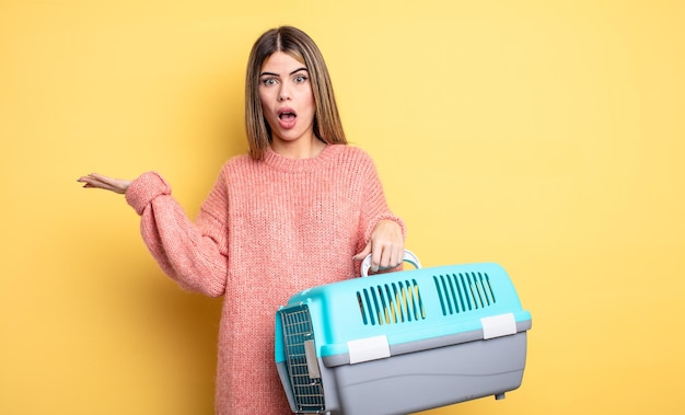 Foto bella donna che sembra sorpresa e scioccata con la mascella caduta in possesso di un concetto di trasportino per animali domestici