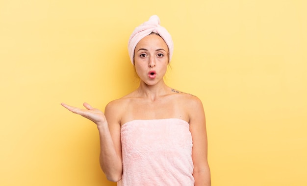 Pretty woman looking surprised and shocked, with jaw dropped holding an object. shower and beauty concept