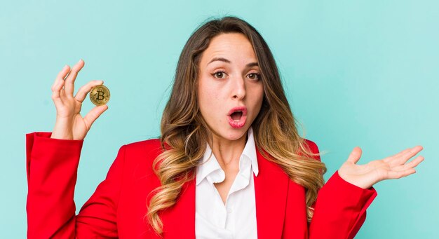 Pretty woman looking surprised and shocked with jaw dropped holding an object