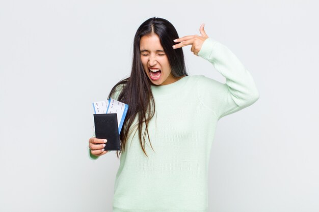 Pretty woman looking unhappy and stressed, suicide gesture making gun sign with hand, pointing to head