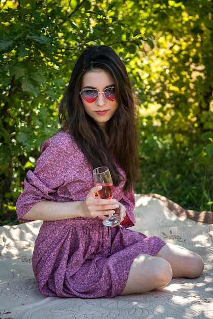 Pretty woman lying on blanket at nature enjoying vacation with wine