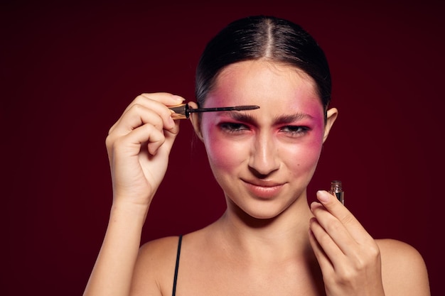 Bella donna trucco spazzola pulita pelle trucco luminoso in posa sfondo rosa inalterato