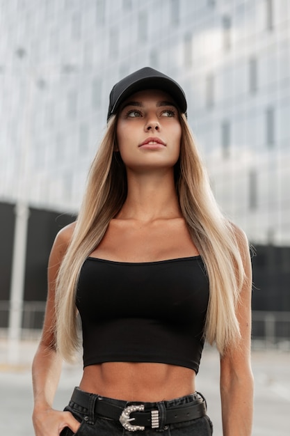pretty woman model in fashion jeans black clothes with black cap walks in the city