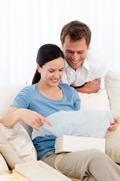 Pretty woman opening a present from her boyfriend on the sofa