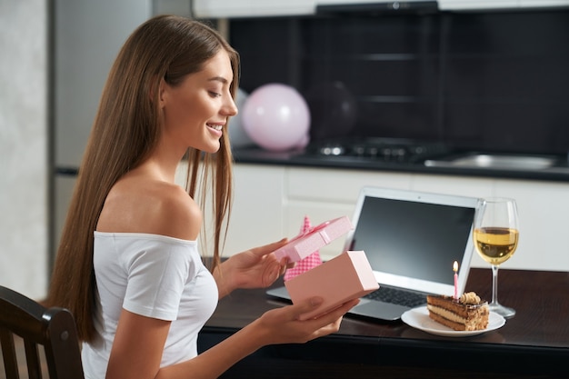 Pretty woman opening present during video call