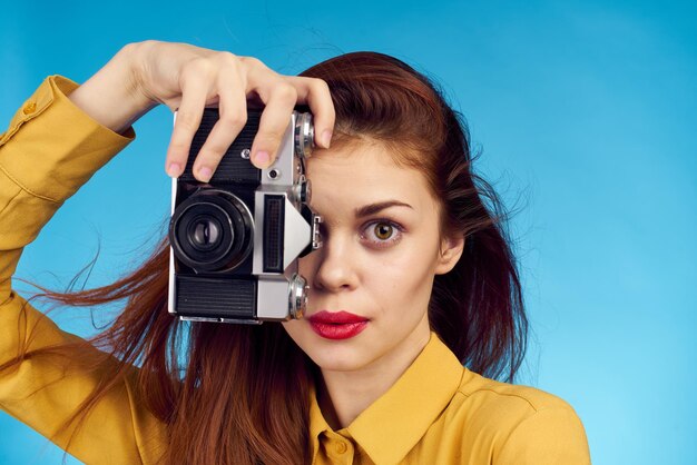 Pretty woman photographer with camera in yellow shirt on blue background person