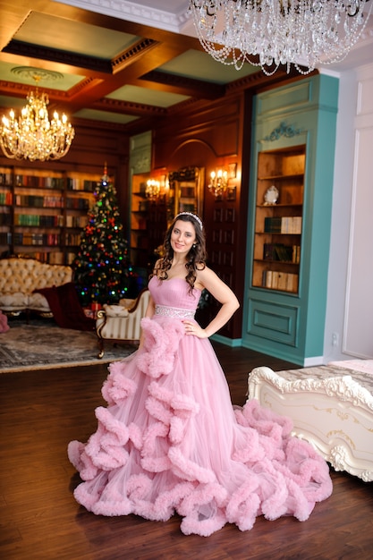 Pretty woman in pink dress near the Christmas tree