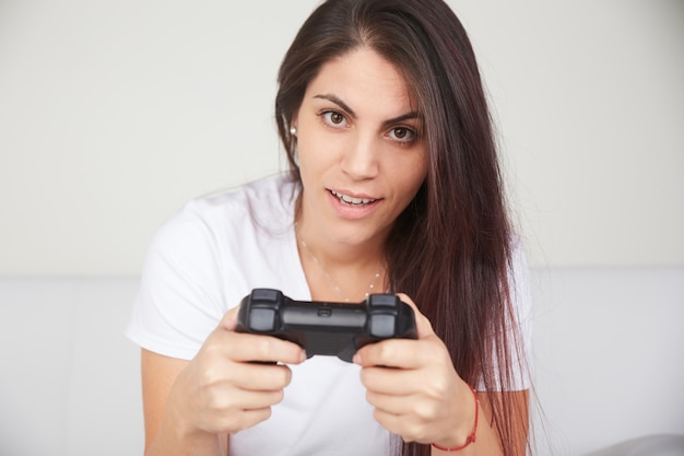 Foto la donna graziosa gioca i videogiochi sul sofà