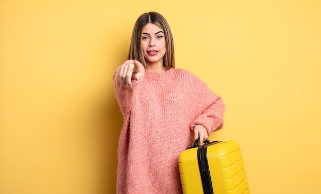 pretty woman pointing at camera choosing you. suitcase travel concept