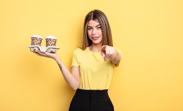 Pretty woman pointing at camera choosing you. take away coffees concept