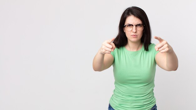 Pretty woman pointing forward at camera with both fingers and angry expression, telling you to do your duty