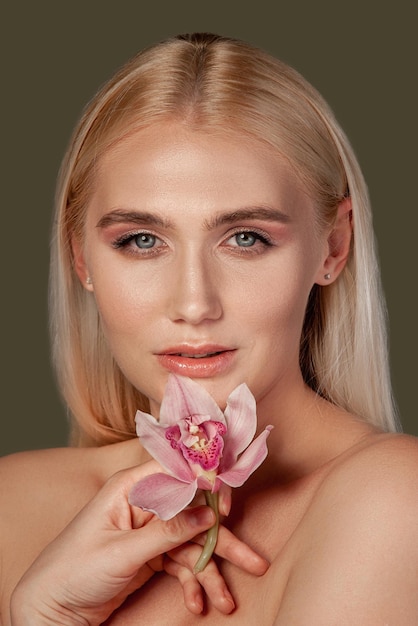 Pretty woman portrait Laser therapy Blonde lady with perfect skin holding orchid flower isolated on brown