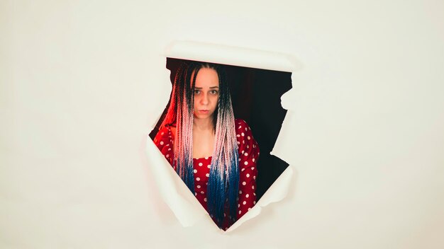 Pretty woman posing in hole of white background in studio Young shy female looking at camera and smiling