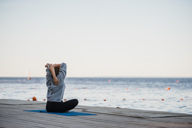 Pretty woman practicing yoga at a lake