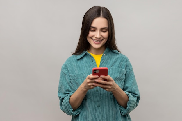 Pretty woman reading message on smartphone and smiling using mobile device for communication