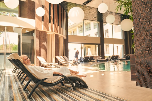 pretty woman relaxing on the deckchair by the swimming pool in spa