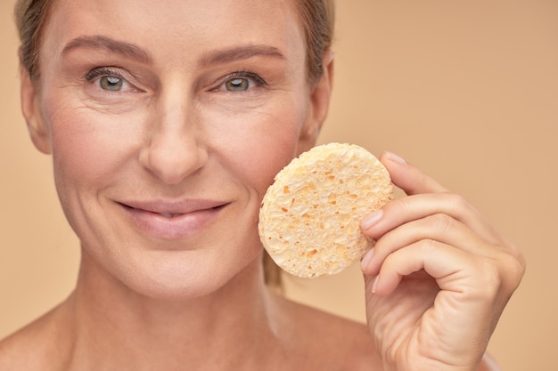 Photo pretty woman removing makeup with a sponge