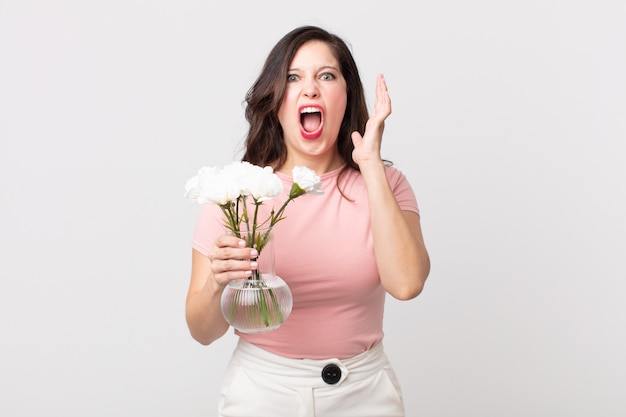 pretty woman screaming with hands up in the air and holding a decorative flowers pot