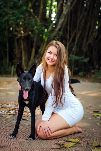 Pretty woman in short dress and black dog playing outdoors