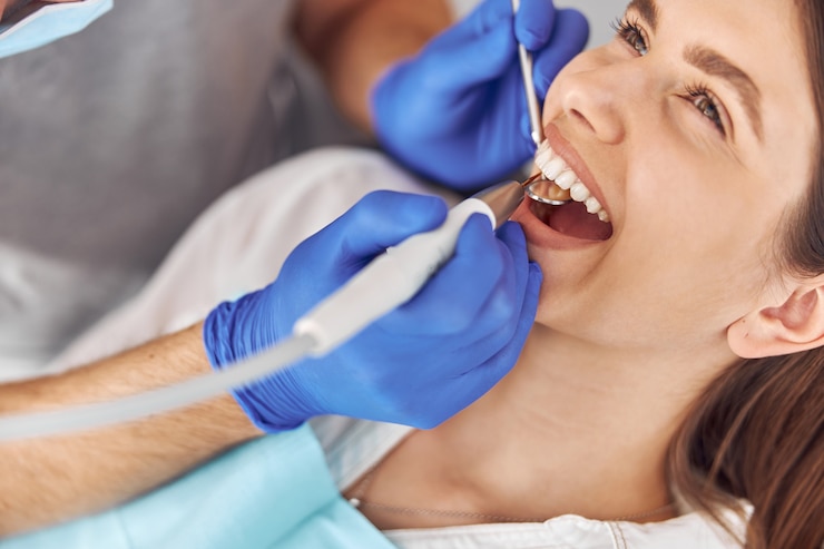 Photo pretty woman sitting in dental chair while professional doctor fixing her teeth.