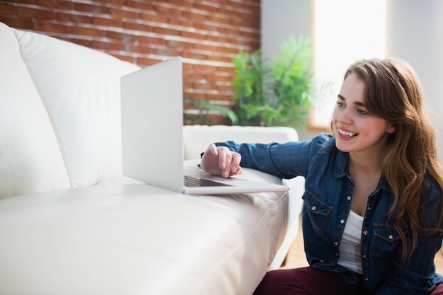 Pretty woman sitting on the floor using laptop in the living room