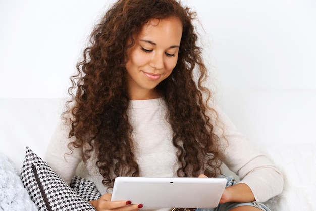 Pretty woman sitting on sofa with white tablet