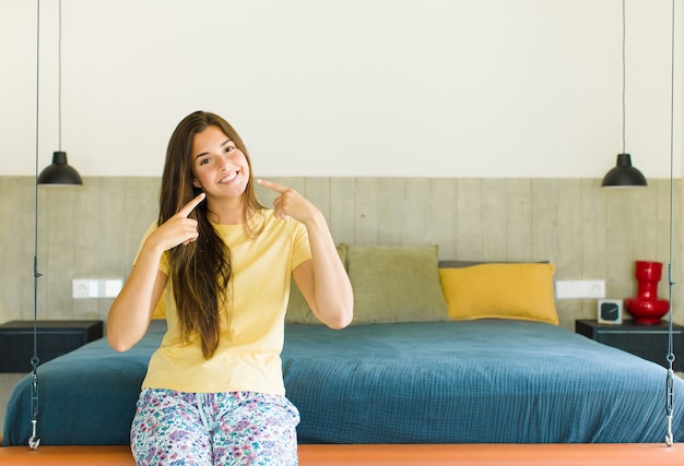 Pretty woman smiling confidently pointing to own broad smile, positive, relaxed, satisfied attitude