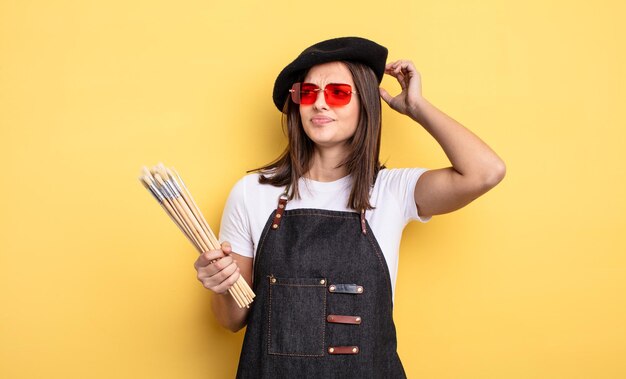 Pretty woman smiling happily and daydreaming or doubting. painter artist concept