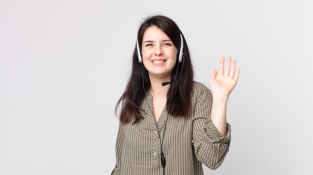 Pretty woman smiling happily, waving hand, welcoming and greeting you. assistant agent with a headset