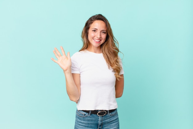 Bella donna che sorride felice, agita la mano, ti dà il benvenuto e ti saluta