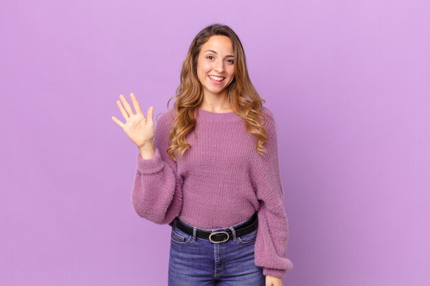 pretty woman smiling happily, waving hand, welcoming and greeting you