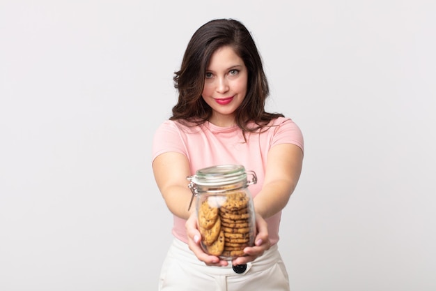 Pretty woman smiling happily with friendly and  offering and showing a concept and holding a cookies glass bottle