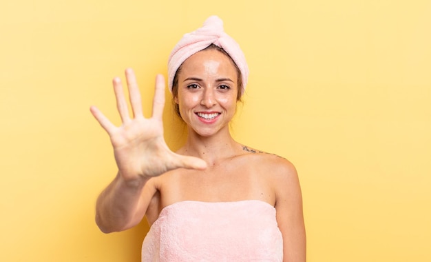 Pretty woman smiling and looking friendly, showing number five. shower and beauty concept