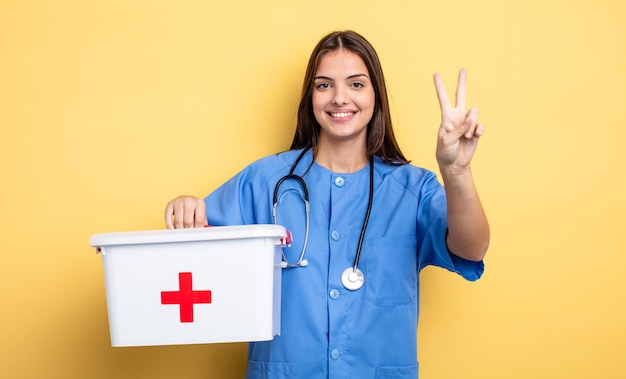 pretty woman smiling and looking happy, gesturing victory or peace. nurse with with a first aid kit nurse