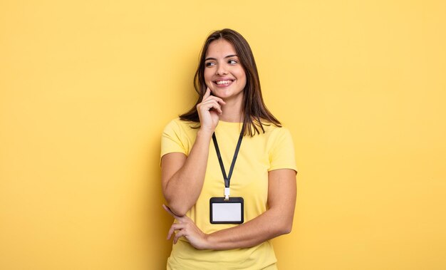 Pretty woman smiling with a happy confident expression with hand on chin accreditation card concept