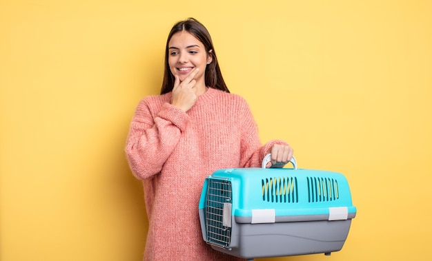 Pretty woman smiling with a happy, confident expression with hand on chin. pet carrier concept