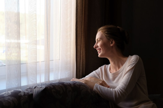 Pretty woman sting at home on the sofa and looking to the window