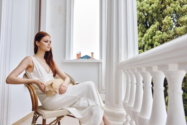 Photo pretty woman stroking a cat sitting in a chair outdoors happy female relaxing high quality photo