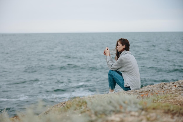 自然リラクゼーションコンセプトを賞賛するきれいな女性のセーター曇り海