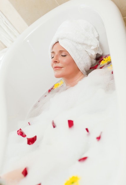 Pretty woman taking a relaxing bath with a towel on her head 