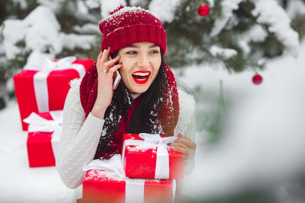Pretty woman talking on a mobile phone and holding christmas presents.
