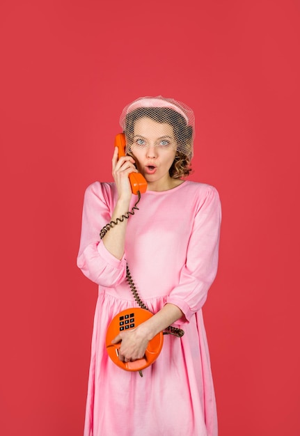 Pretty woman talking at retro handset girl talking on landline phone surprised woman holds handset