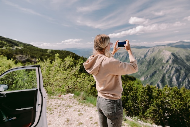 Photo pretty woman travel by car and using smartphone on road trip vacations in mountains.